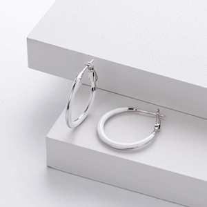 Macro shot of 925 sterling silver hoop earrings with white enamel on minimalist cubes