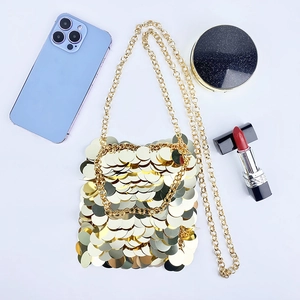 Detailed macro shot of golden sequin mini bag with metallic chain strap on white background