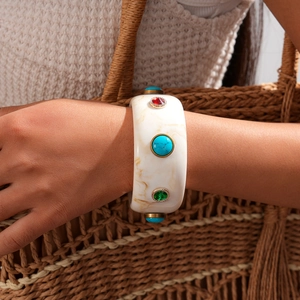 Detail of a wide marble resin bangle with turquoise and colorful gemstones in gold setting