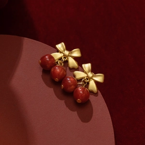 Elegant bow stud earrings with deep red beads in a stylish vintage gold finish