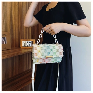 Détail d'un sac à carreaux en tweed avec chaîne acrylique porté sur une robe noire