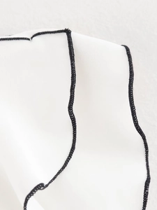 Close-up of white fabric texture with premium black overlock stitching detail on the edges