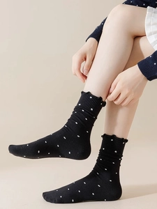 Detail of black polka dot socks with ruffled lettuce edge trim and soft cotton texture