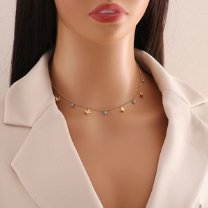 Close-up of golden butterfly necklace with turquoise beads on a model's neck