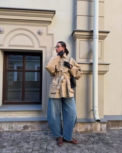 Outdoor shot of beige belted trench coat with large pockets and classic lapel collar