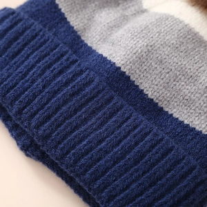 Close-up of winter knitted beanie with blue, grey, and white striped patterns and ribbed edge