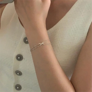 Detail of a double-layered 925 sterling silver twisted knot bracelet on a woman wrist
