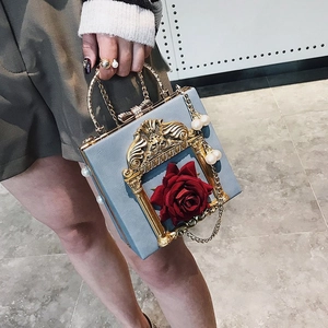 Detail of light blue crossbody bag with 3D red rose and elegant pearl handle