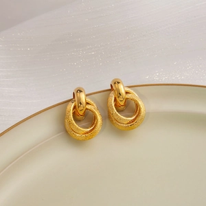 Modern gold geometric intertwined hoop earrings on minimalist ceramic plate