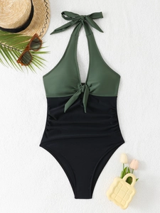 Detailed view of olive green and black halter swimsuit with twist knot and ruched sides
