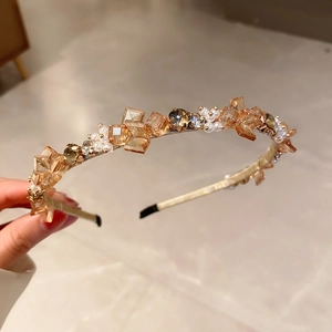 Close-up of champagne crystal and white pearl embellishments on a slim metal headband
