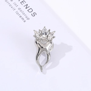 Macro shot of silver tooth brooch with clear zircon crown on minimalist background