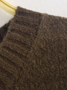 Close-up of soft dark brown knit sweater texture showing plush wool and ribbed cuff detail