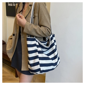 Close-up of blue and white striped canvas tote bag worn on shoulder in a cafe setting