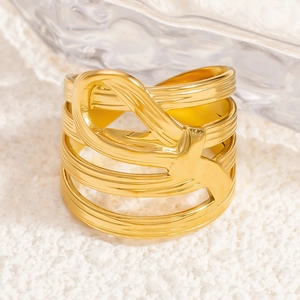 Close-up of golden multi-layer hollowed-out ring with intricate bow design on white surface
