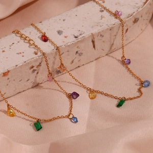 Macro shot of 18K gold plated chain with multi-colored faceted zircon stones on silk