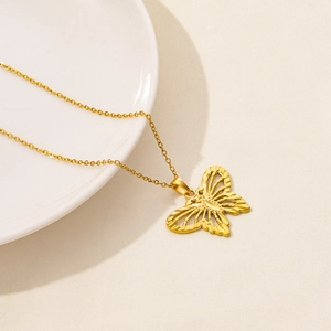 Detailed macro view of a gold stainless steel necklace with a hollow butterfly pendant