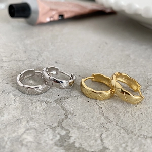 Macro detail of S925 sterling silver hoop earrings with a quilted texture in gold and silver