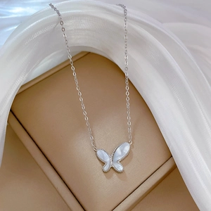 Close-up of a silver butterfly necklace with mother of pearl inlay on a silk gift box