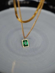 Detail of a double-layered gold snake chain necklace with an emerald zircon pendant