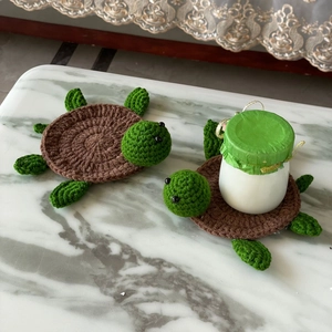 Detail of handmade crochet turtle coasters on marble desk showing soft yarn texture