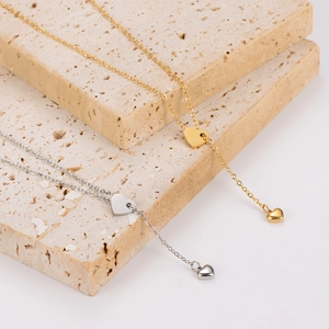Minimalistische Edelstahl-Halskette mit Herz-Quaste in Gold und Silber auf Stein