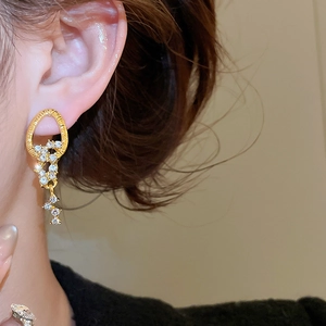 Close-up of gold tassel earrings with clear rhinestones on a model for a vintage look