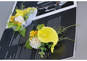 Close-up of yellow calla lily boutonniere with daisy and green berries on a magazine