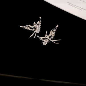 Macro shot of silver swallow stud earrings with sparkling cubic zirconia and liquid metal style