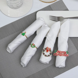 Detail of Christmas napkin rings featuring reindeer, trees and bells on white napkins