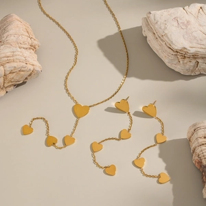Elegant gold stainless steel jewelry set featuring heart pendants and tassel details
