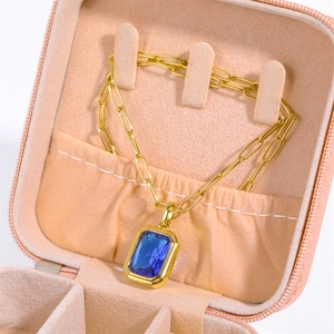 Close-up of gold paperclip chain necklace with blue gemstone in a pink velvet jewelry box