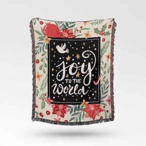 Close-up of woven Christmas blanket with Joy to the World text and red floral patterns