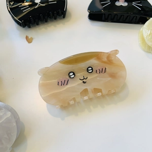 Close-up of beige marble cat hair claw clip made of acetate with cute face details