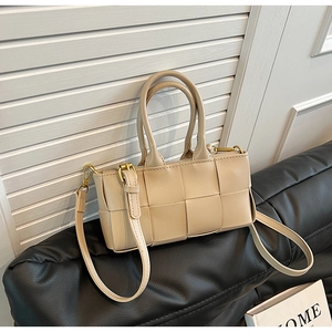 Dettaglio borsa a mano intrecciata in pelle PU beige su divano con tracolla regolabile