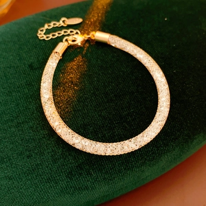 Détail du bracelet en maille dorée avec zircons et breloque cœur sur velours