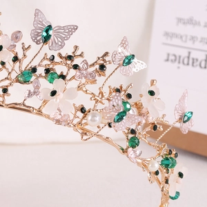 Macro detail of golden baroque bridal crown with green crystals and butterfly accents