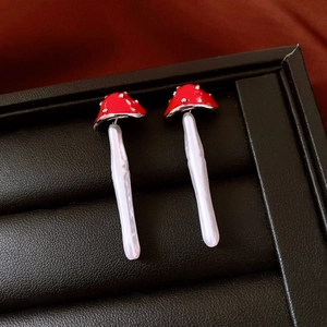 Detail of mushroom drop earrings with red enamel caps and white faux pearl stems