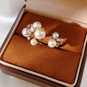 Detail view of asymmetric pearl earrings with zircon inlay in a jewelry box