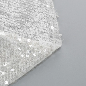Close-up of white sequin embroidery and mesh lace detail on an elegant evening gown