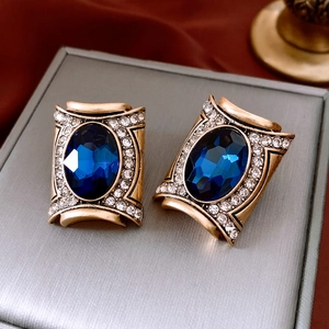 Macro shot of vintage style earrings with deep blue gemstones and sparkling rhinestones