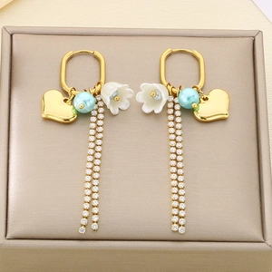 Detail of heart charm earrings with lily of the valley and zircon tassel chains