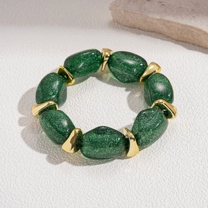 Detail of green acrylic beads with golden geometric spacers on a retro beaded bracelet