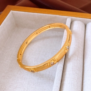 Detailed macro view of 24K gold-plated floral bangle with starburst floral engravings