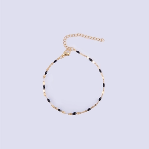 Detailed close-up of golden lip chain with black enamel beads and lobster clasp