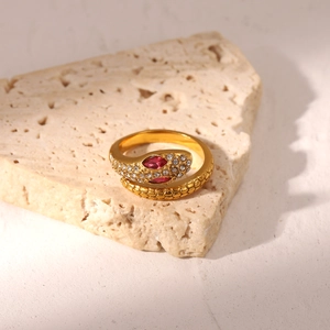 Macro detail of 18K gold snake ring with red gemstone eyes and cubic zirconia