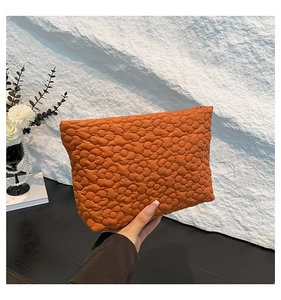Detail of orange quilted pouch featuring floral texture and soft padded fabric finish