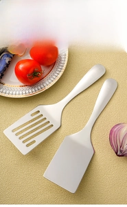 Detail of 304 stainless steel spatula set with solid and slotted heads on kitchen counter