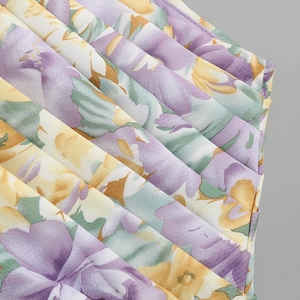 Macro detail of pleated floral fabric in purple and yellow hues for summer dress
