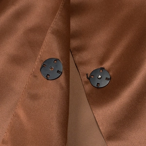 Detail of black metal snap buttons on a brown elegant puff sleeve blouse for women